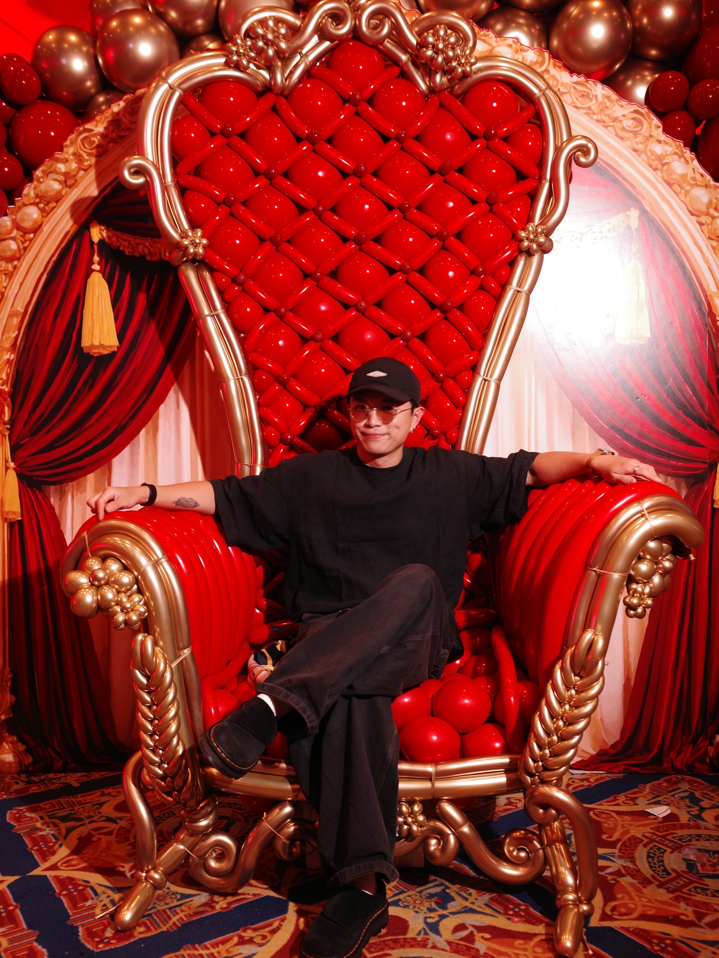 Ting Yu Wong sentado en un trono de globos rojo y dorado